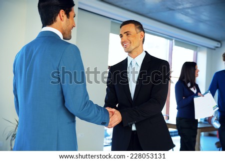Two happy businessman handshaking in conference hall