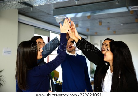 Happy business team is holding hands together. Raising one hand up