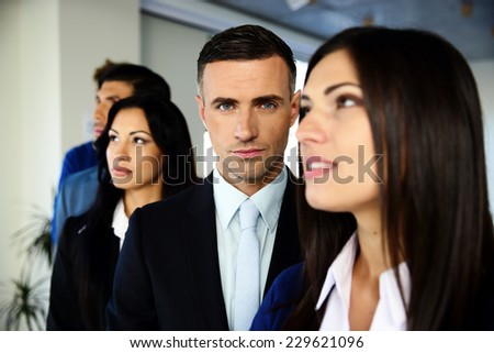 Group of young co-workers standing in a row at office