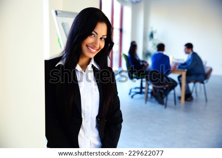 Smiling businesswoman standing in front of a business meeting
