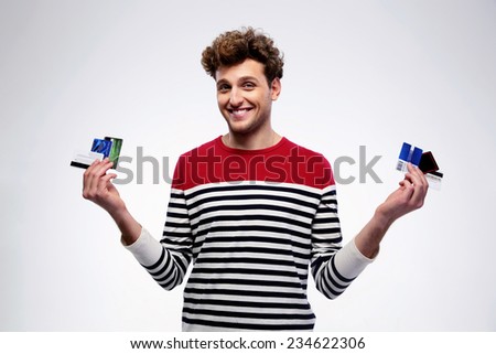 Happy casual man holding credit cards over gray background