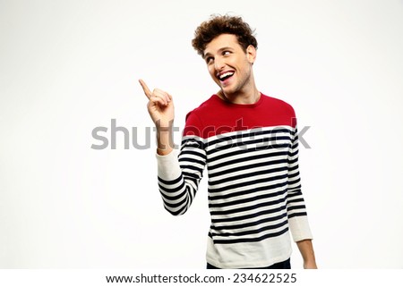 Happy casual man pointing upwards over gray background