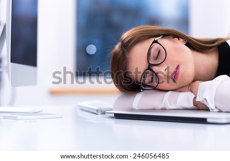 Young businesswoman in glasses sleeping at her workplace