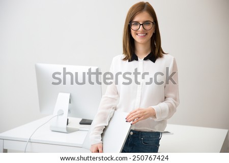 Smiling beautiful businesswoman standing with laptop in front of her workplace