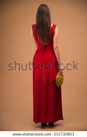 Back view portrait of a fashion woman in red dress over brown background