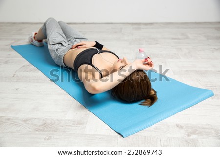 Beautiful woman lying on the yoga mat at gym