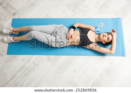 Top view portrait of a young woman lying on the yoga mat at gym