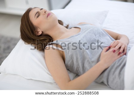 Young woman in pain lying on the bed