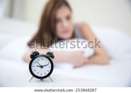 Woman waking up in the morning and looking on alarm clock. Focus on clock