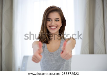 Portrait of a happy woman with thumbs up at home