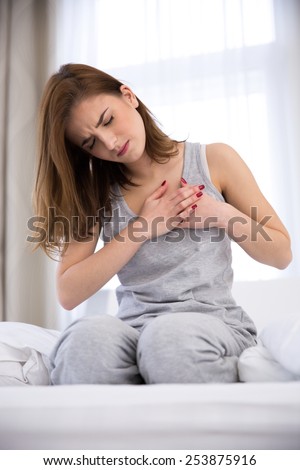 Young woman in pajamas having pain in heart