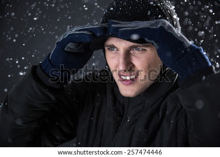 Handsome man looking away with snow on background