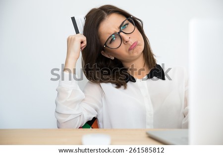 Thoughtful businesswoman sitting at the table with bank card