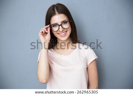 Smiling young woman with glasses over gray background