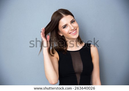 Portrait of a smiling woman touching her hairs over gray background