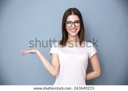 Happy young woman in glasses presenting something on the hand