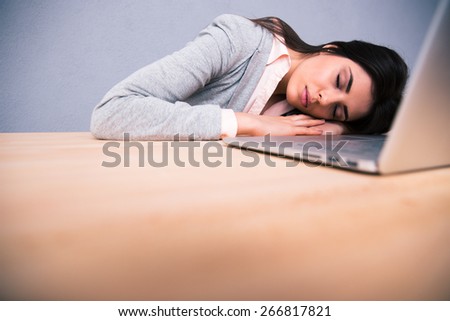 Young pretty woman sleeping on the table with laptop