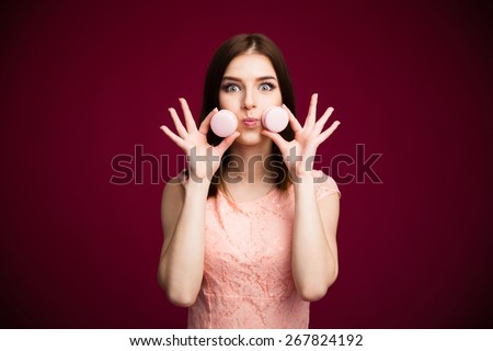 Young funny woman holding cookies over pink background. Looking at camera