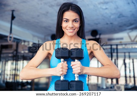 Happy fit woman holding dumbbells at gym