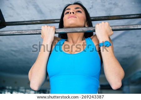 Beautiful fit woman working out on horizontal bar at gym