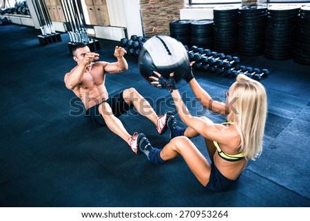Muscular man and woman workout with fitball at gym