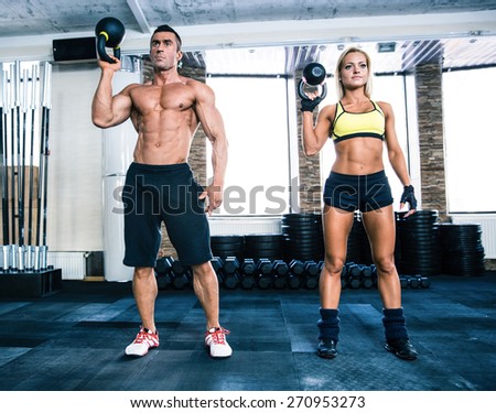 Muscular man and fit woman workout with kettle ball at gym