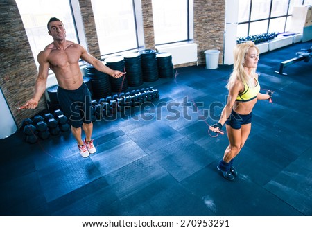 Fitness man and woman workout with jumping rope in crossfit gym