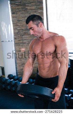 Handsome muscular man holding weight in gym