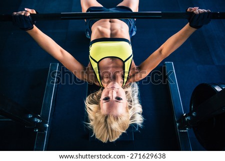 Fitness woman workout with barbell on bench in gym