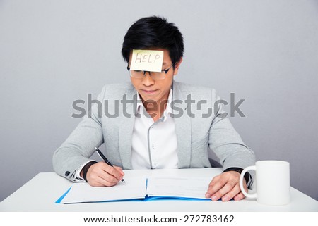 Businessman sitting at the table and writing something in document with adhesive note