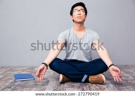 Young asian man sitting on the floor and meditating