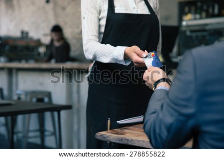 Closeup image of a man giving credit card to waiter in cafe