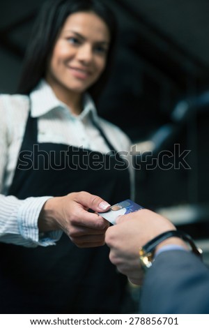 Man giving bank card to female waiter in cafe. Focus on card