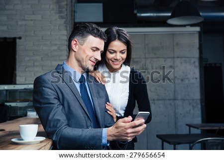 Happy beautiful couple using smartphone in restaurant