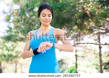 Happy sporty woman using smart watch outdoors