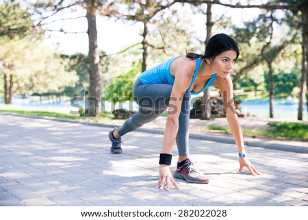 Fitness woman runner in start position outdoor