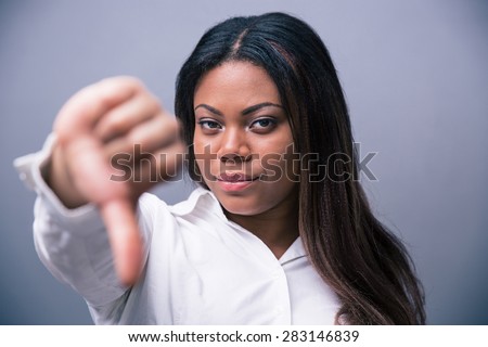 African businesswoman showing thumb down over gray background