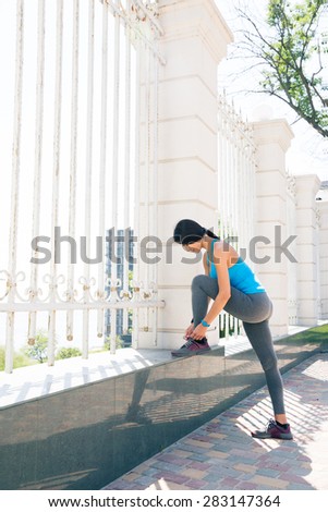 Full length portrait of a young woman runner tying shoelaces