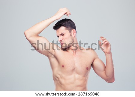 Man sniffing his armpit over gray background