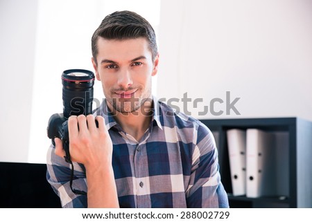 Happy young man in shirt holding photo camera
