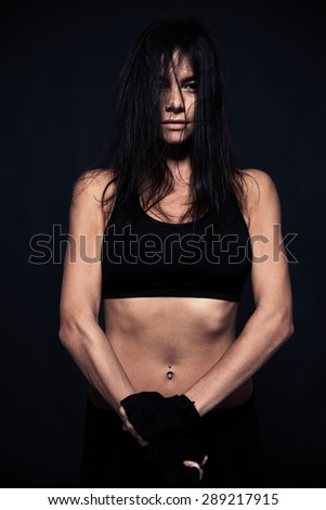 Portrait of exhausted woman standing over black background. Looking at camera