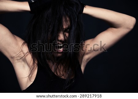 Portrait of a fitness woman screaming over black background