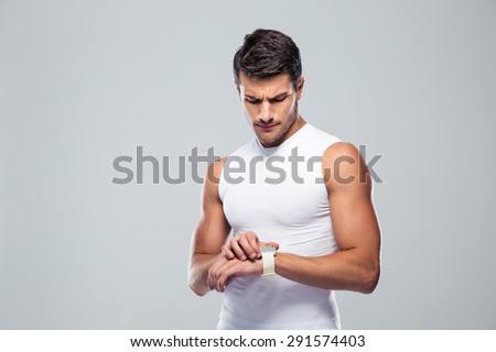Handsome sports man using smart watch over gray background