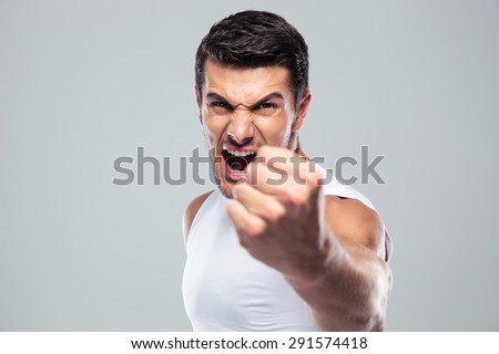 Angry man screaming and showing fist over gray background