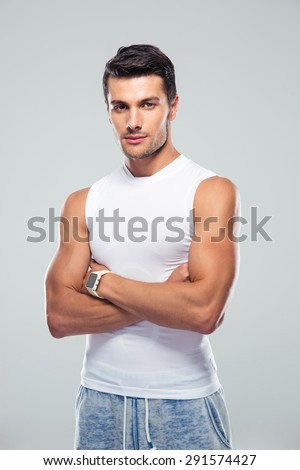 Handsome young man standing with arms folded over gray background over gray background