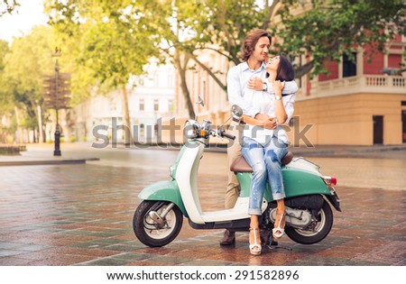 Happy beautiful couple on scooter in old european city