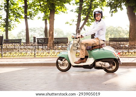 Trendy man driving a scooter in helmet in old town