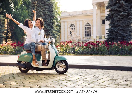 Happy young couple traveling in scooter in old european city