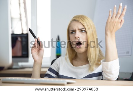 Angry young woman working on computer in office