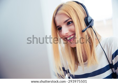 Happy young girl in headset using desktop computer in office